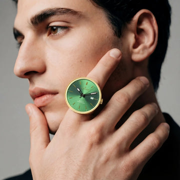 Eine elegante, goldfarbene Uhr mit einem lebendigen grünen Zifferblatt und minimalistischen schwarzen Zeigern.